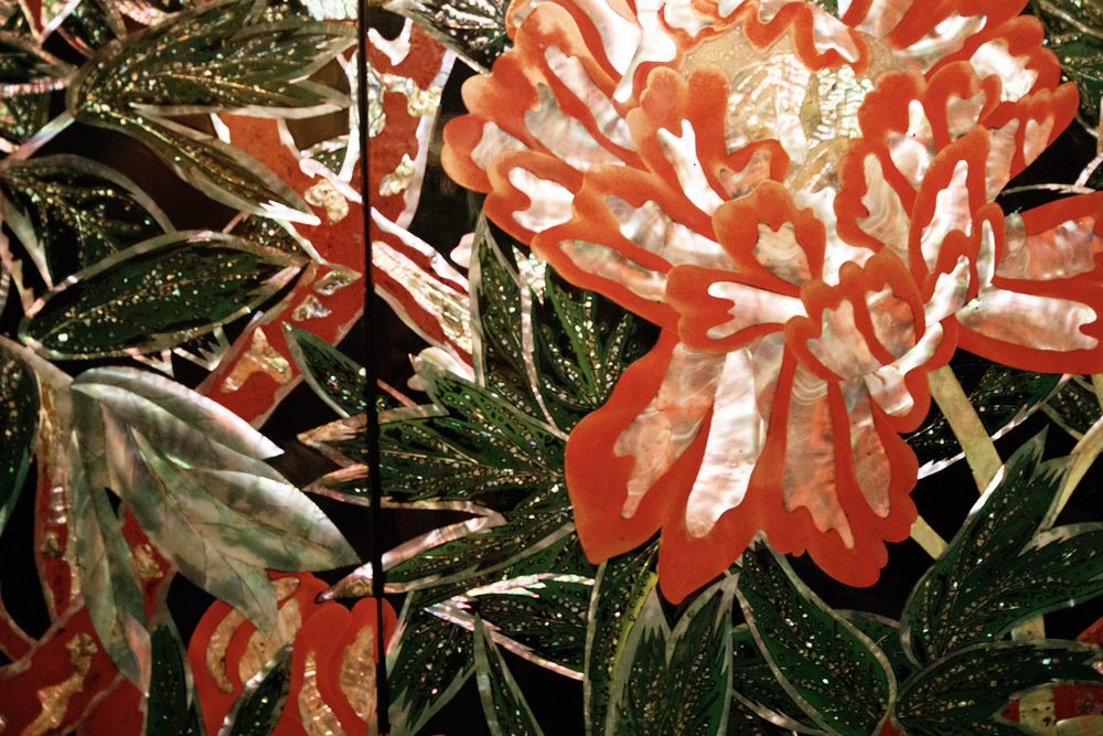Large peonies in red, white and green mother-of-pearl set into black lacquer on a decorated panel